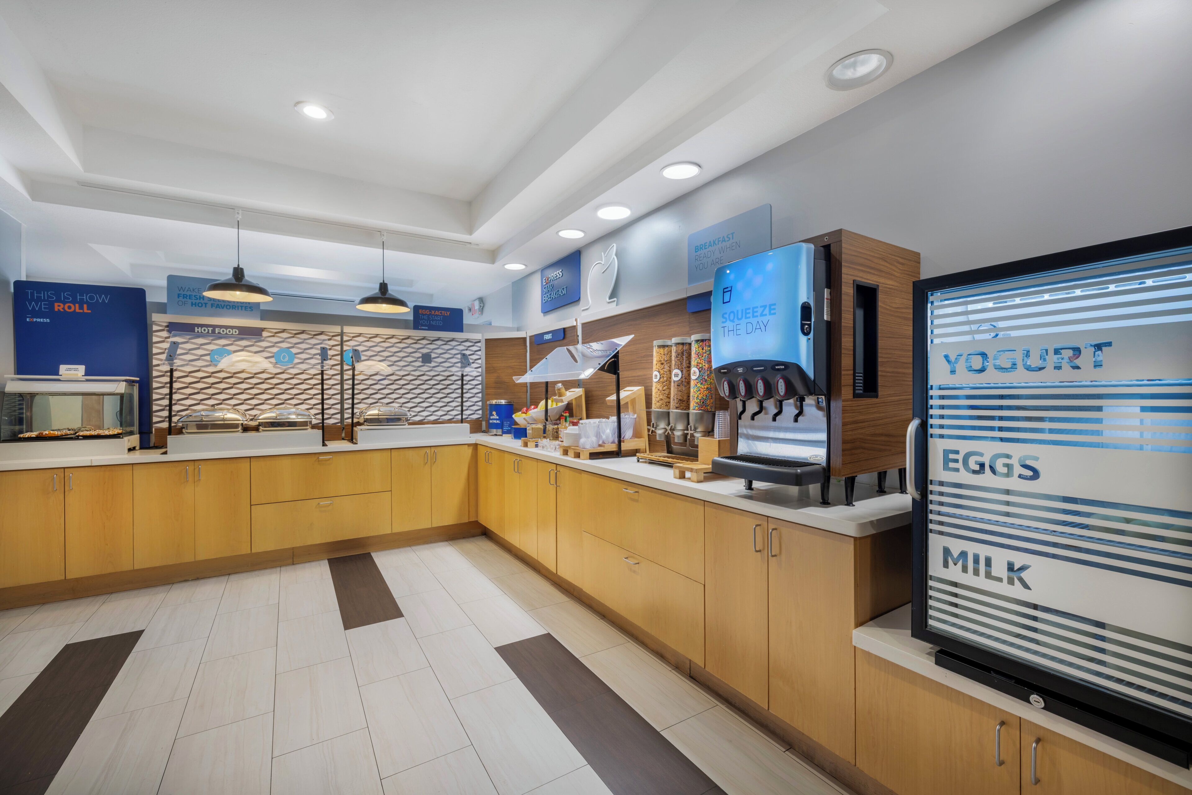 A modern breakfast area with a yogurt dispenser, a coffee machine, and a sign indicating the availability of eggs and milk.