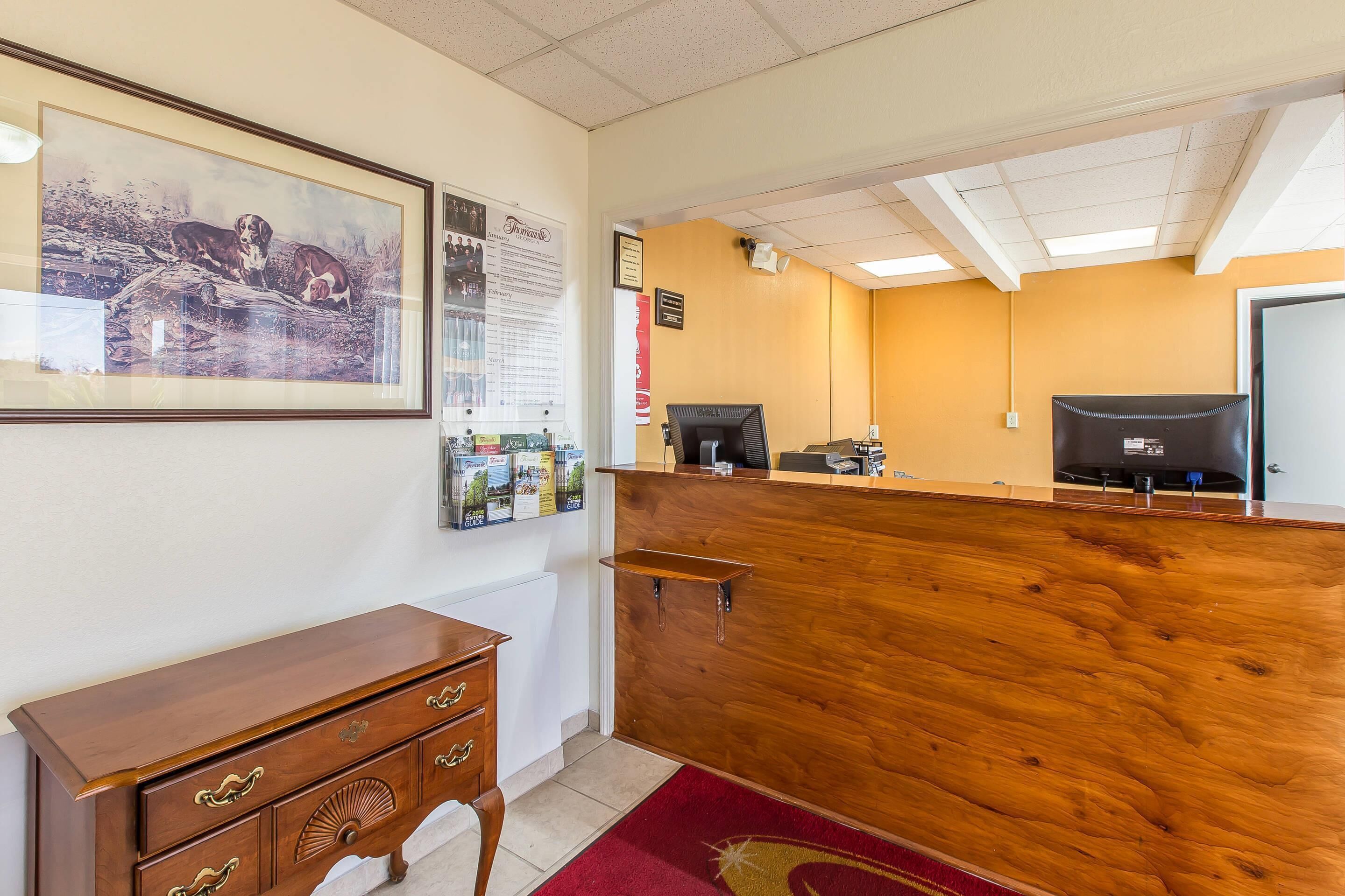 A reception area with a wooden desk, a framed picture on the wall, and a bulletin board with notices.