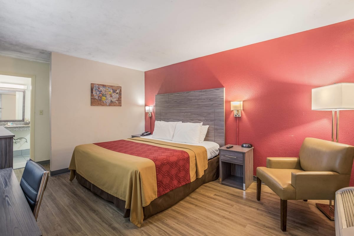 Een hotelkamer met een bed, een stoel, een bureau en een nachtkastje.