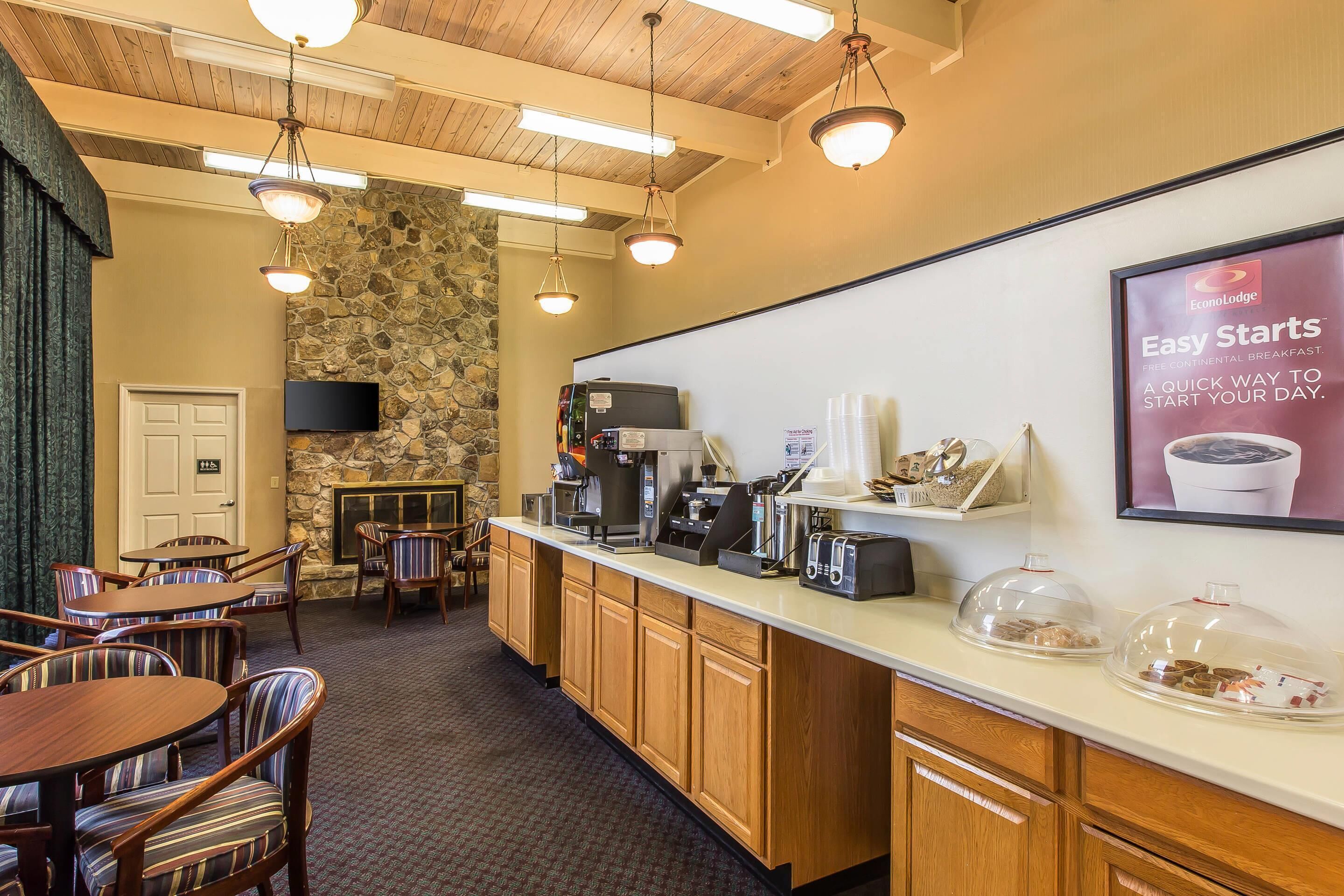 A hotel lobby with a stone wall, wooden ceiling, and a coffee station.