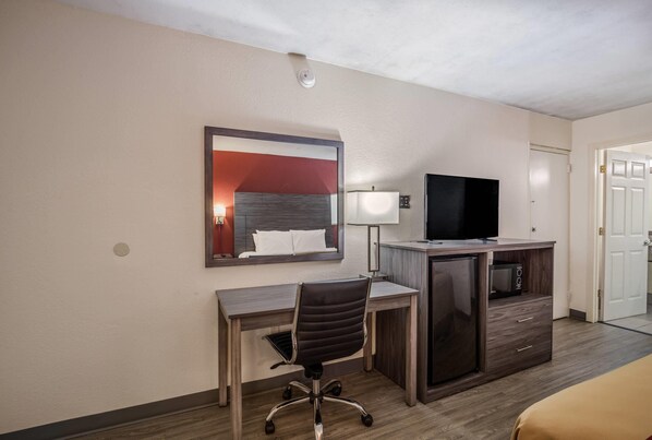 A hotel room with a desk, chair, television, and a mirror reflecting a bed. - Econo Lodge Thomasville (Thomasville)
