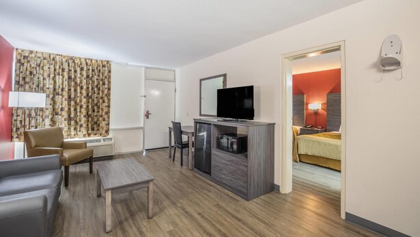 A hotel room with a TV, a desk, a chair, a bed, and a bathroom visible through an open door. - Econo Lodge Thomasville (Thomasville)