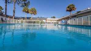 A swimming pool with a clear blue water surface, surrounded by a white fence, with palm trees and a building in the background. - Econo Lodge Thomasville (Thomasville)