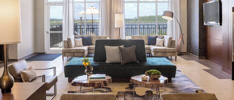 Ein modernes Hotelzimmer mit einem großen Bett, zwei Sofas, einem Couchtisch und einem Fernseher.