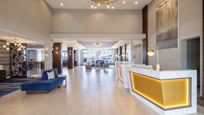 A spacious lobby with a reception desk, seating area, and a large window providing a view of the outdoors.
