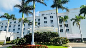 A hotel with a white facade, palm trees, and a landscaped garden.