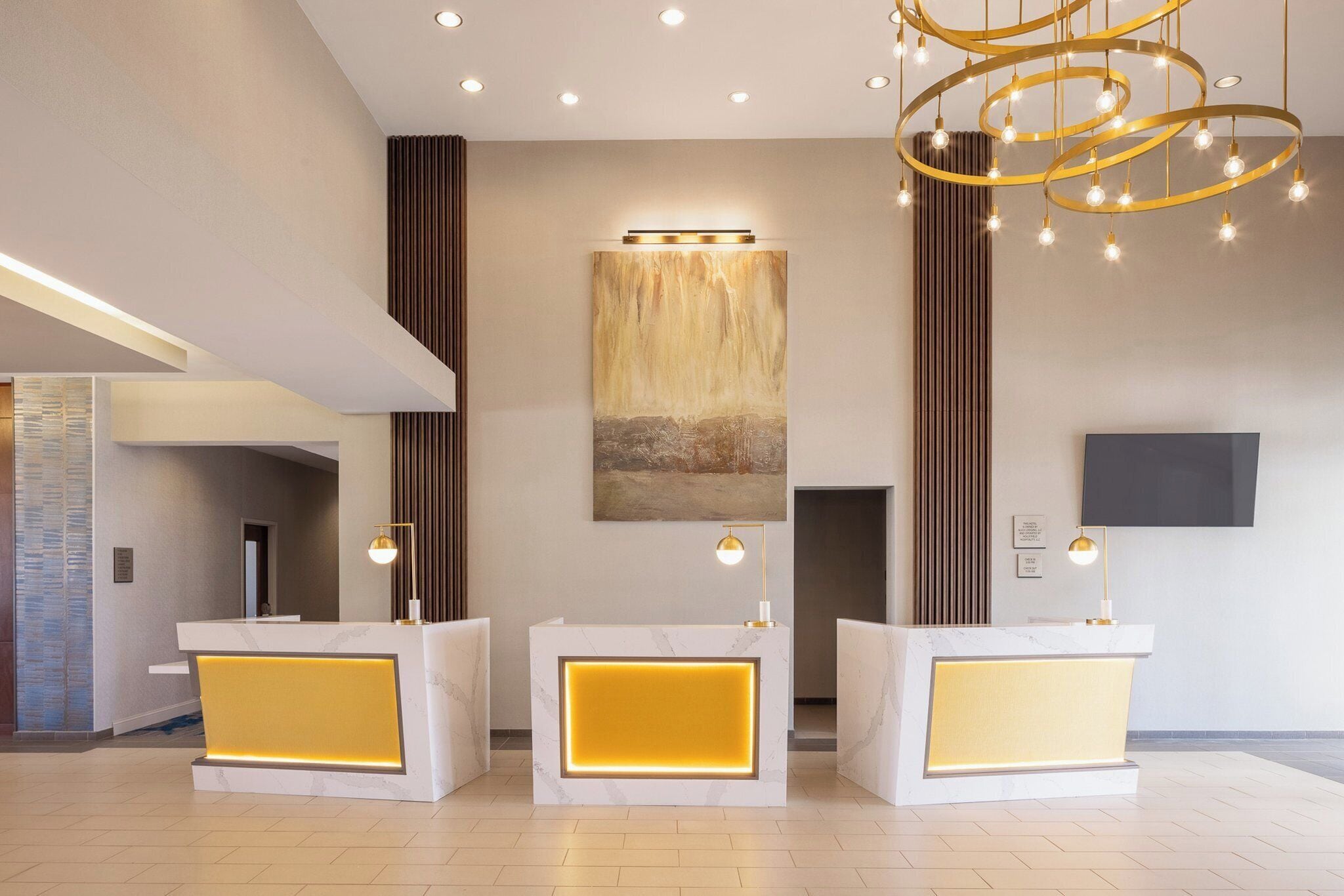 A reception area with a marble reception desk, a large abstract painting, and a modern chandelier.