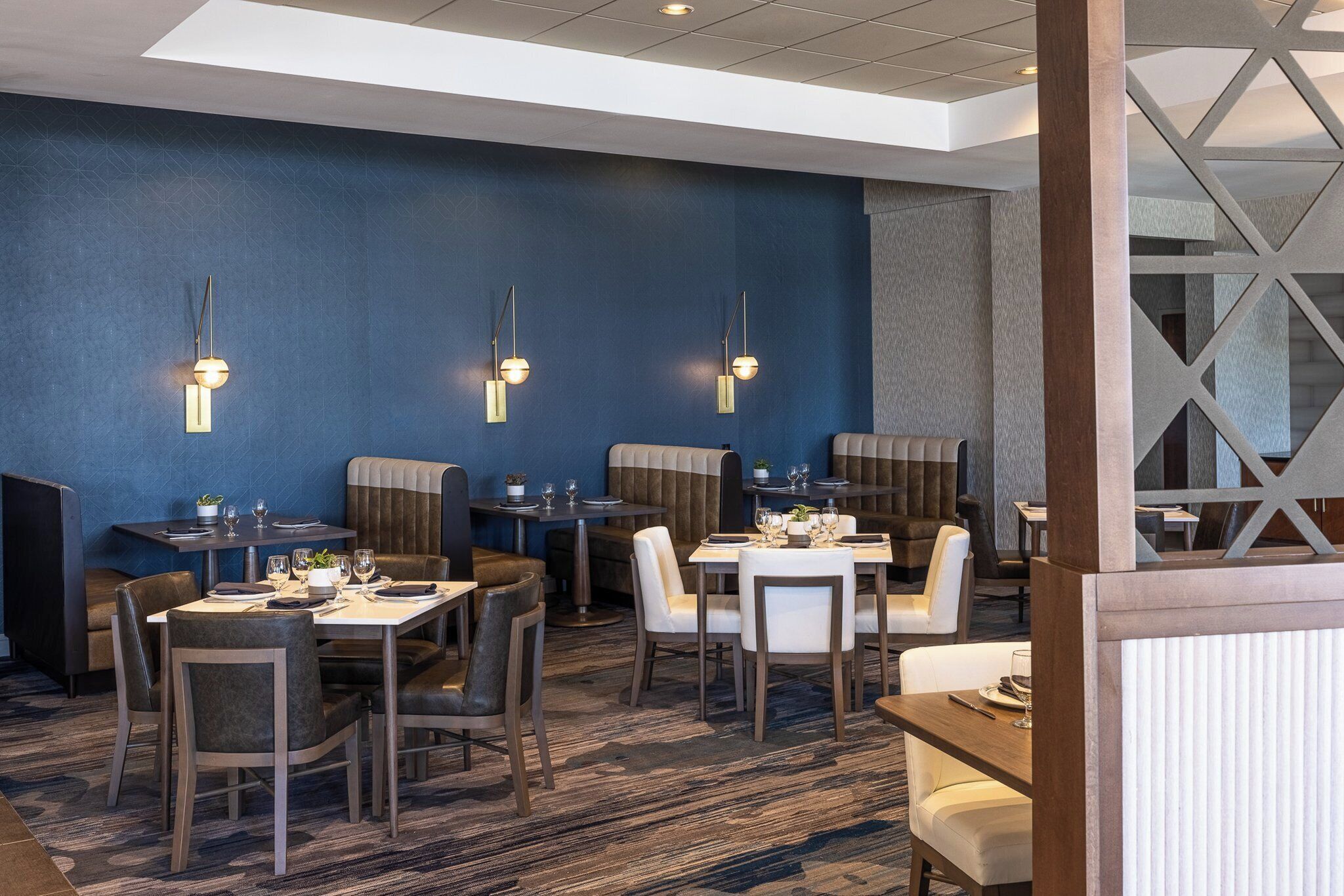 A modern restaurant with booths and tables, pendant lighting, and a blue accent wall.