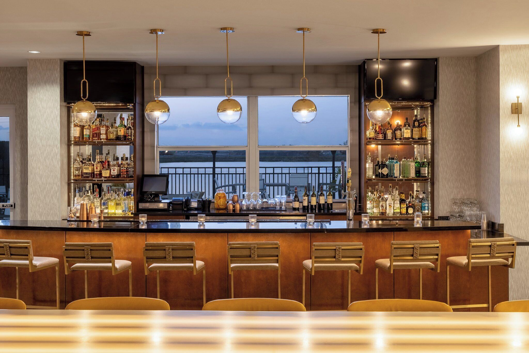A bar area with a counter, bar stools, and shelves of bottles.