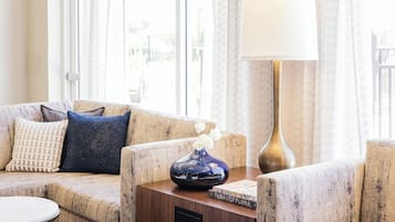 A living room with a sofa, a small table, a vase with flowers, and a lamp.