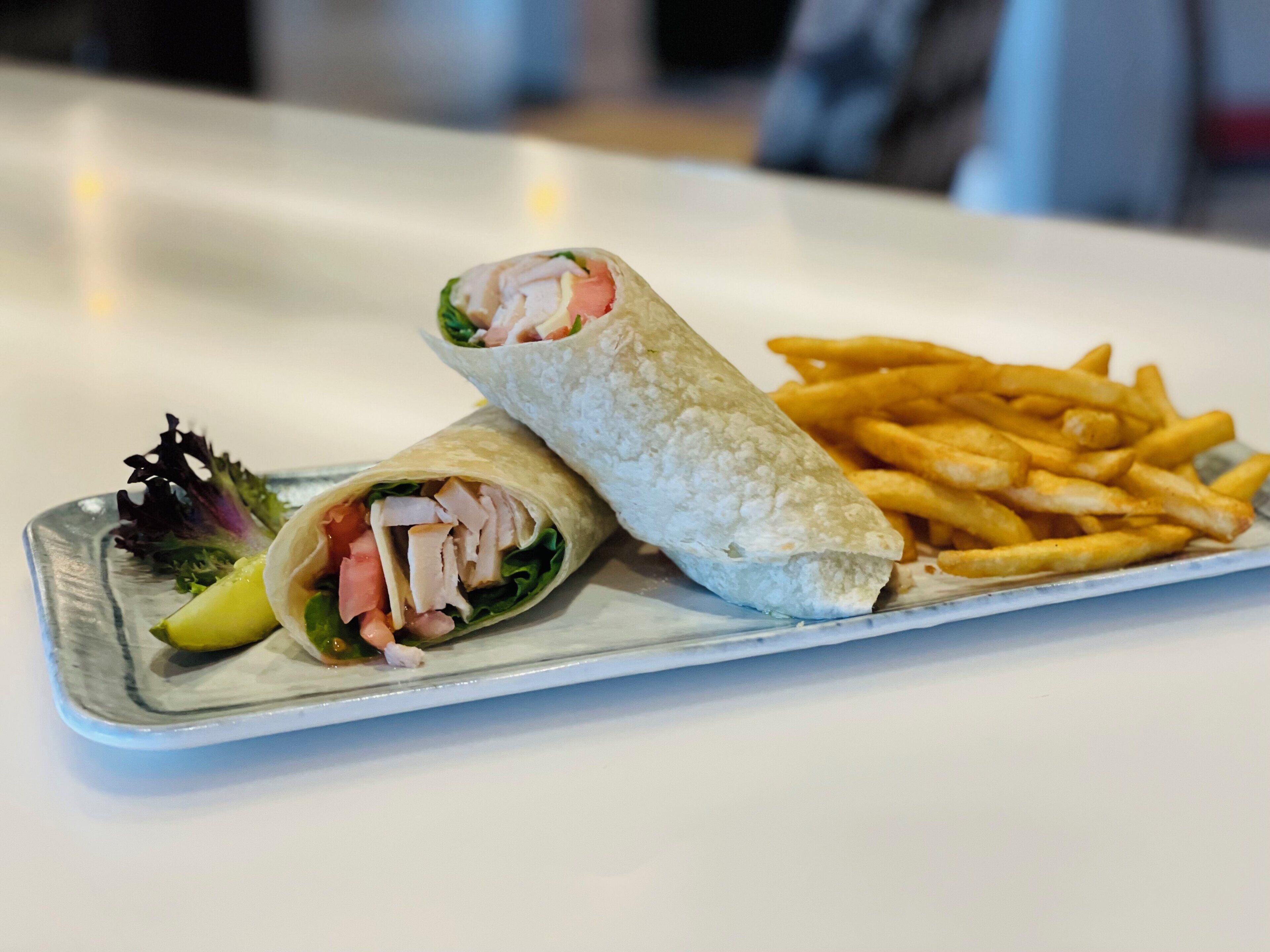 A plate with a wrap, fries, and a small salad.