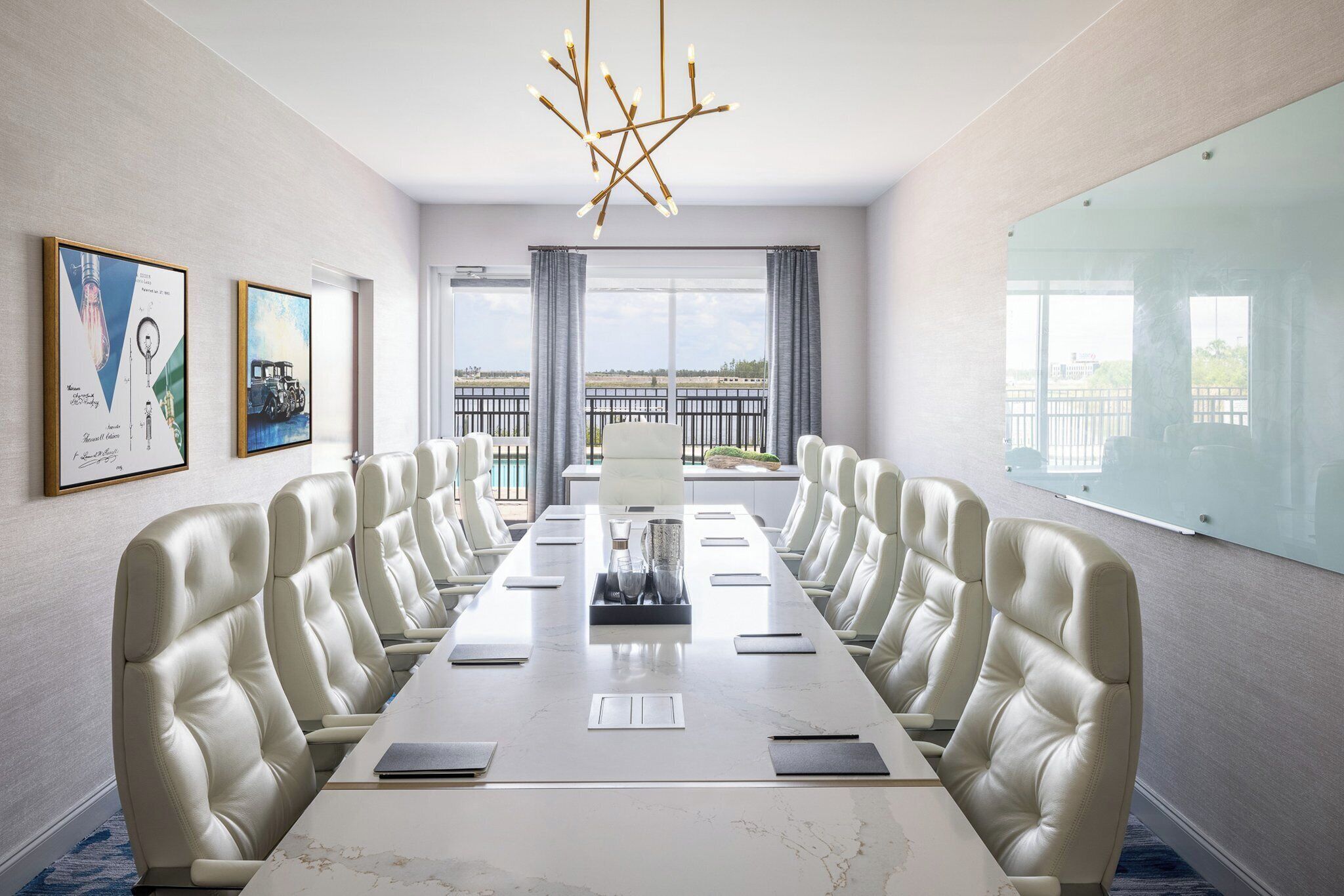 Une salle de conférence dotée d’une longue table, de fauteuils en cuir, d’un lustre, d’œuvres d’art encadrées et d’une grande fenêtre offrant une vue panoramique.
