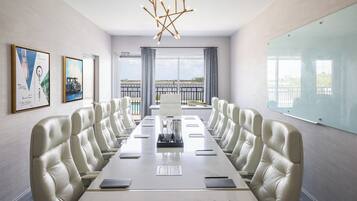 Une salle de conférence dotée d’une longue table, de fauteuils en cuir, d’un lustre, d’œuvres d’art encadrées et d’une grande fenêtre offrant une vue panoramique.