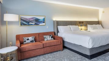A hotel room with a bed, a sofa, a lamp, and a painting on the wall.