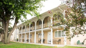 Un immeuble à plusieurs étages doté d’un espace extérieur couvert avec des sièges, de nombreux balcons et d’une façade en briques.