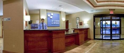 A reception area with a wooden reception desk, a blue sign, and a revolving door.