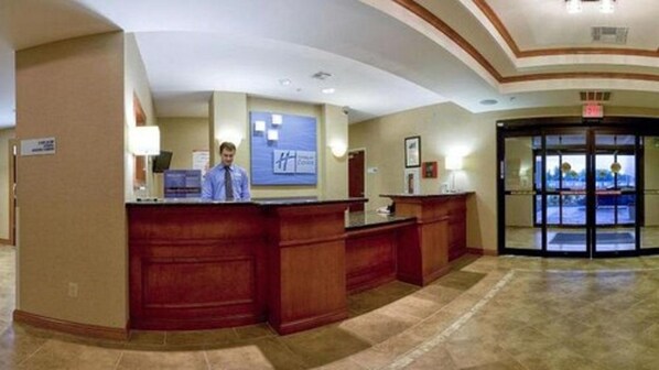 A reception area with a wooden reception desk, a blue sign, and a revolving door. - Holiday Inn Express Hotel & Suites Bartlesville by IHG (Bartlesville)