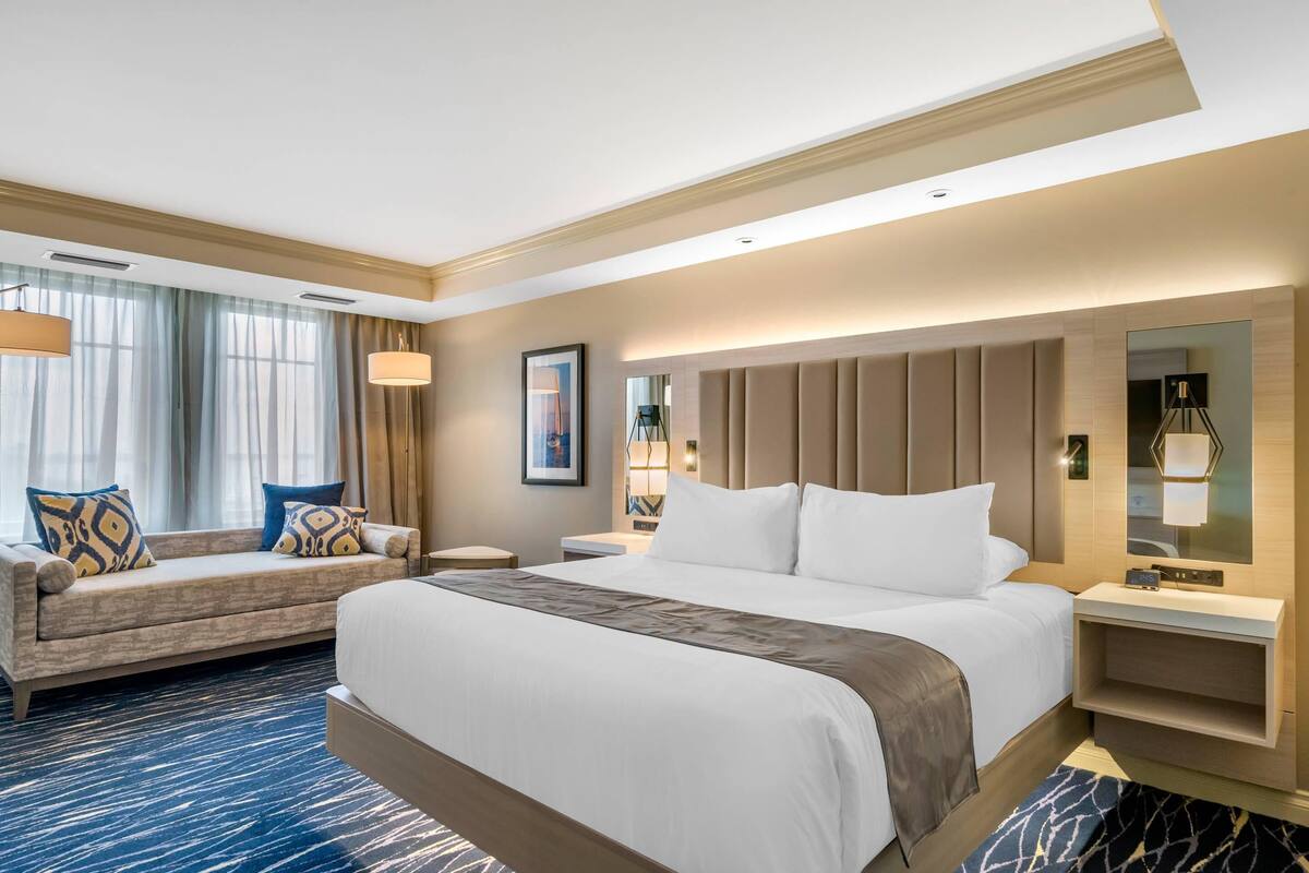 Una habitación de hotel con una cama grande, un sofá, un escritorio y un espejo.
