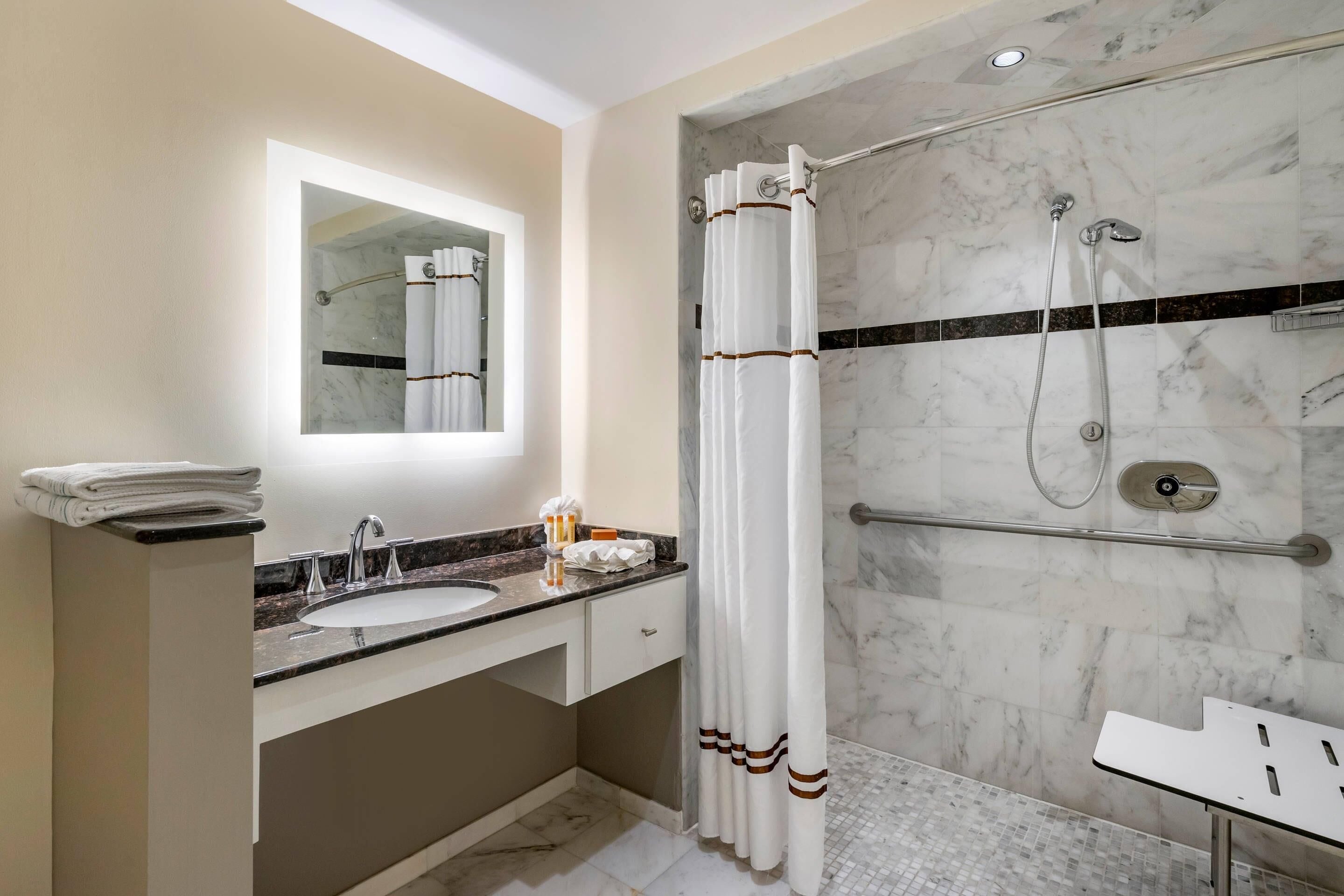 A modern bathroom with a marble shower, a sink, and a mirror.