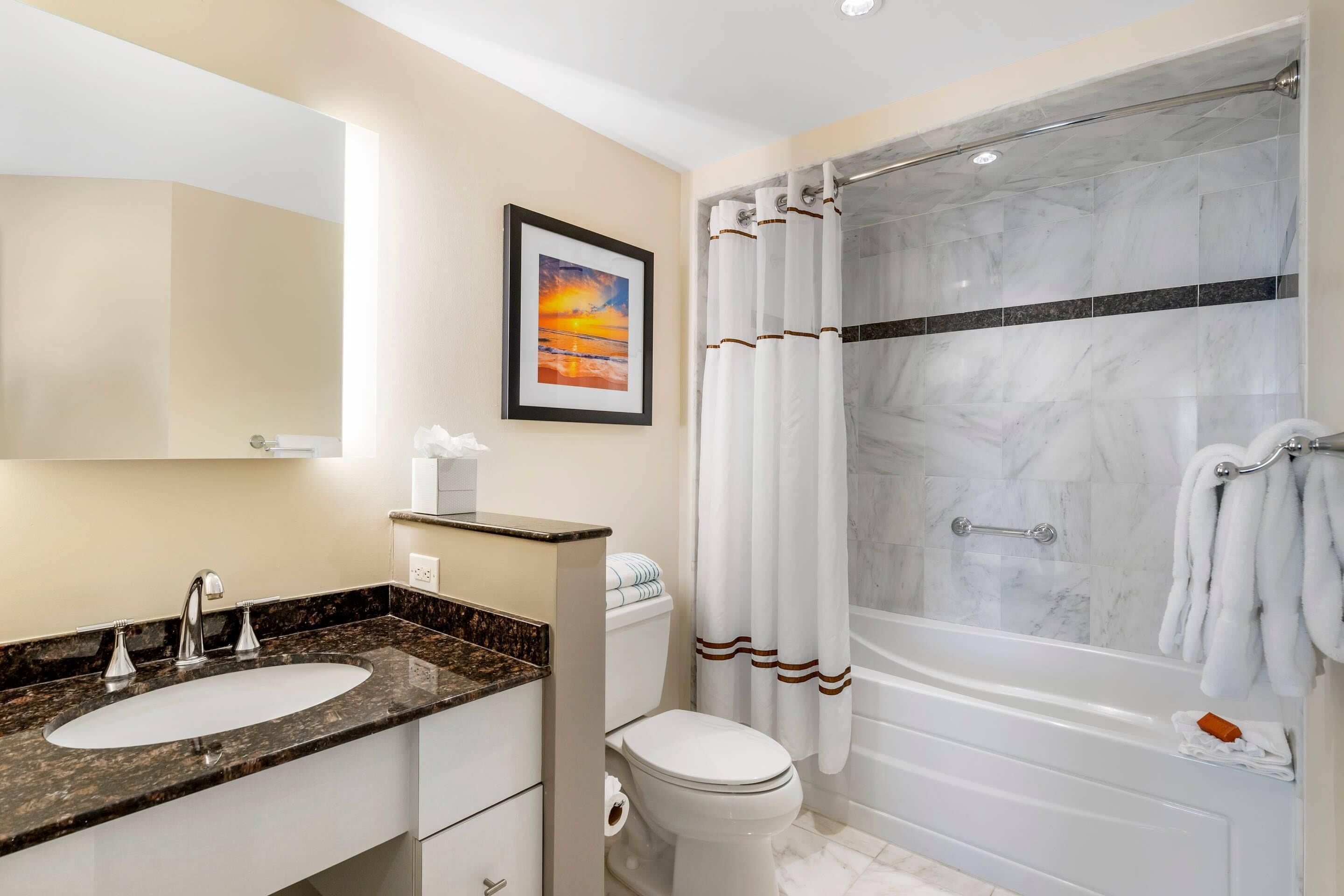 A bathroom with a marble sink, a toilet, and a walk-in shower with a glass door.