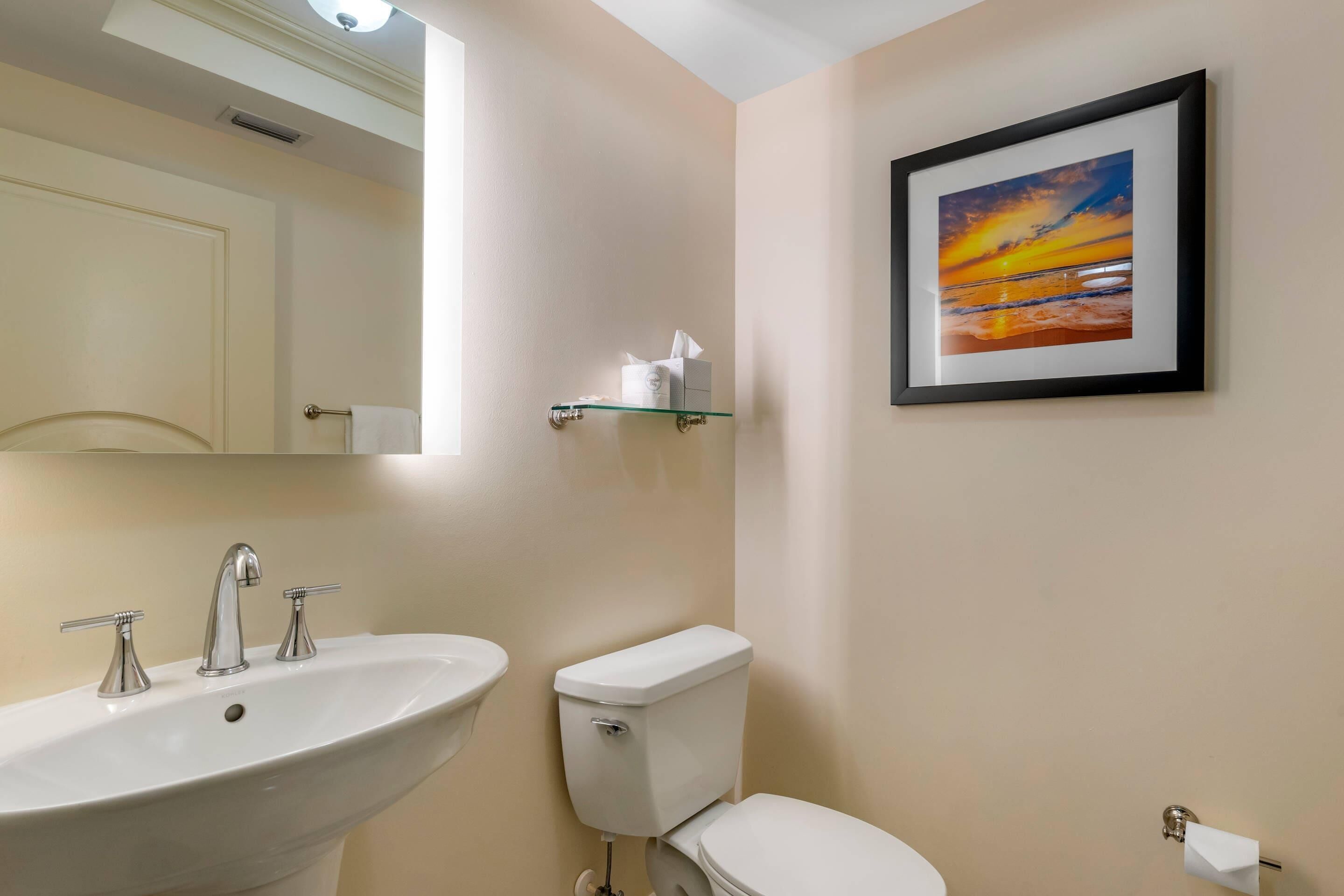 Un baño con lavamanos, inodoro y un cuadro en la pared.