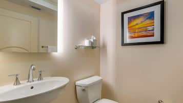 Un baño con lavamanos, inodoro y un cuadro en la pared.