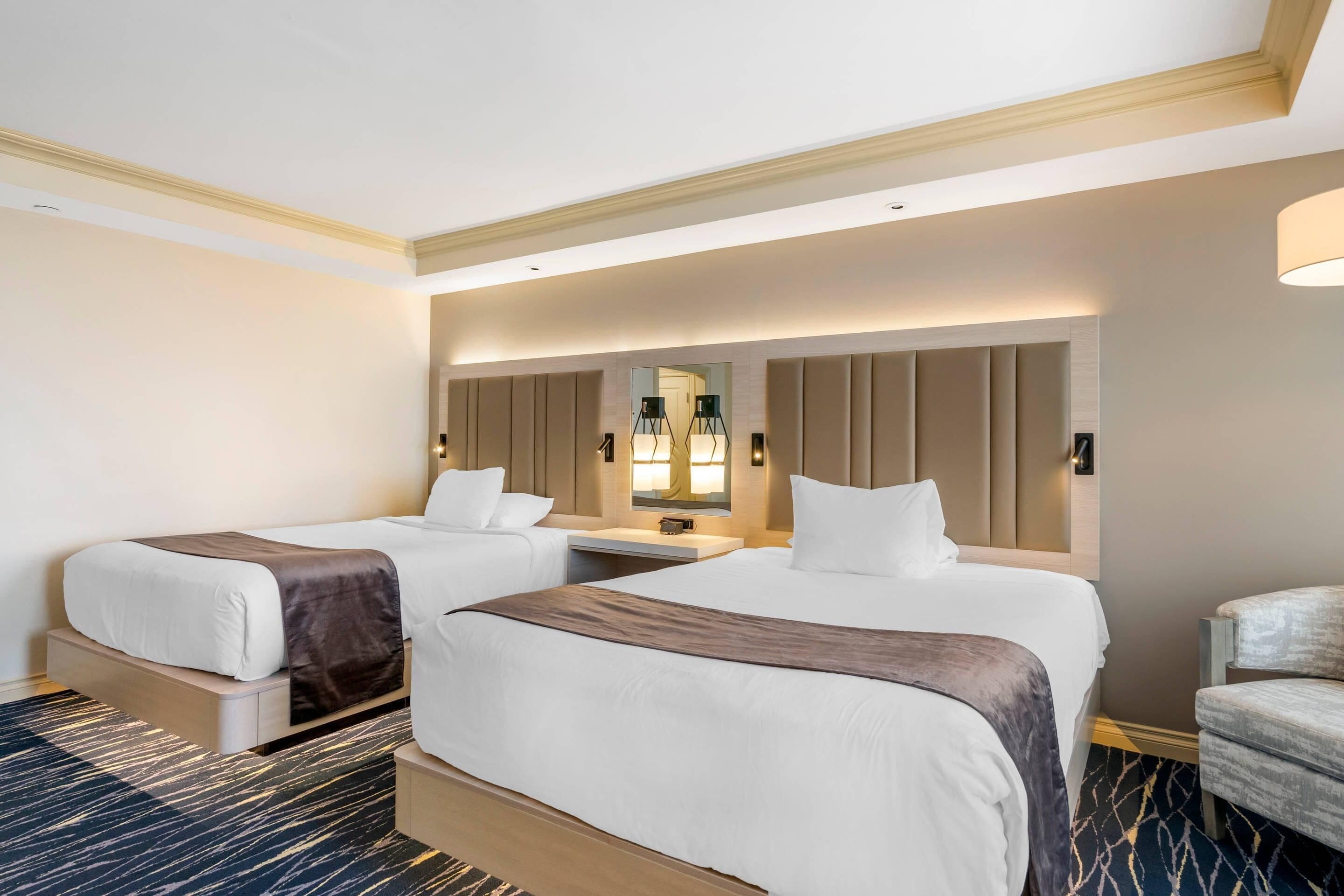 Ein Hotelzimmer mit zwei Betten, einem großen Spiegel und einer Sitzecke.