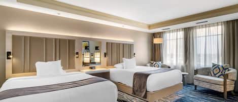 Une chambre d’hôtel avec deux lits, un canapé, un grand miroir et une vue sur l’extérieur.