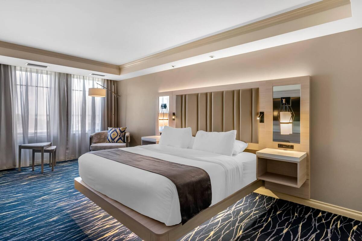 Habitación de hotel moderna con una cama grande, un escritorio y un espejo.