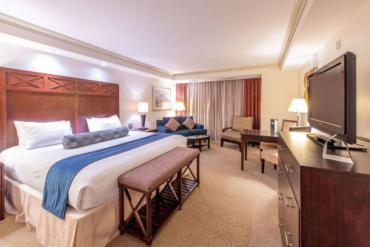 Una habitación de hotel con cama, escritorio, televisión y zona de estar.