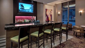Zona de bar con una pantalla de televisión, barra y asientos.