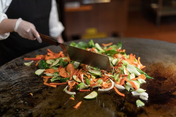 Un chef picando verduras sobre una tabla de cortar grande.