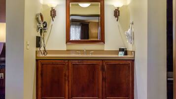 A bathroom with a wooden vanity, a mirror, and two wall-mounted lights.