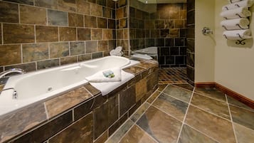 Ein Badezimmer mit einer großen Badewanne, einer Duschkabine und Fliesenboden.