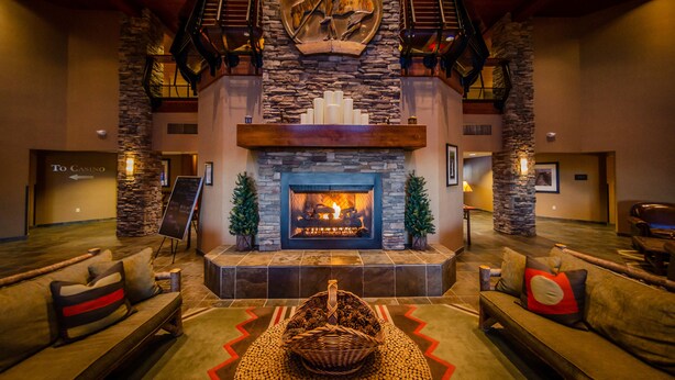 A spacious lobby with a stone fireplace, comfortable seating, and a staircase leading to an upper level.