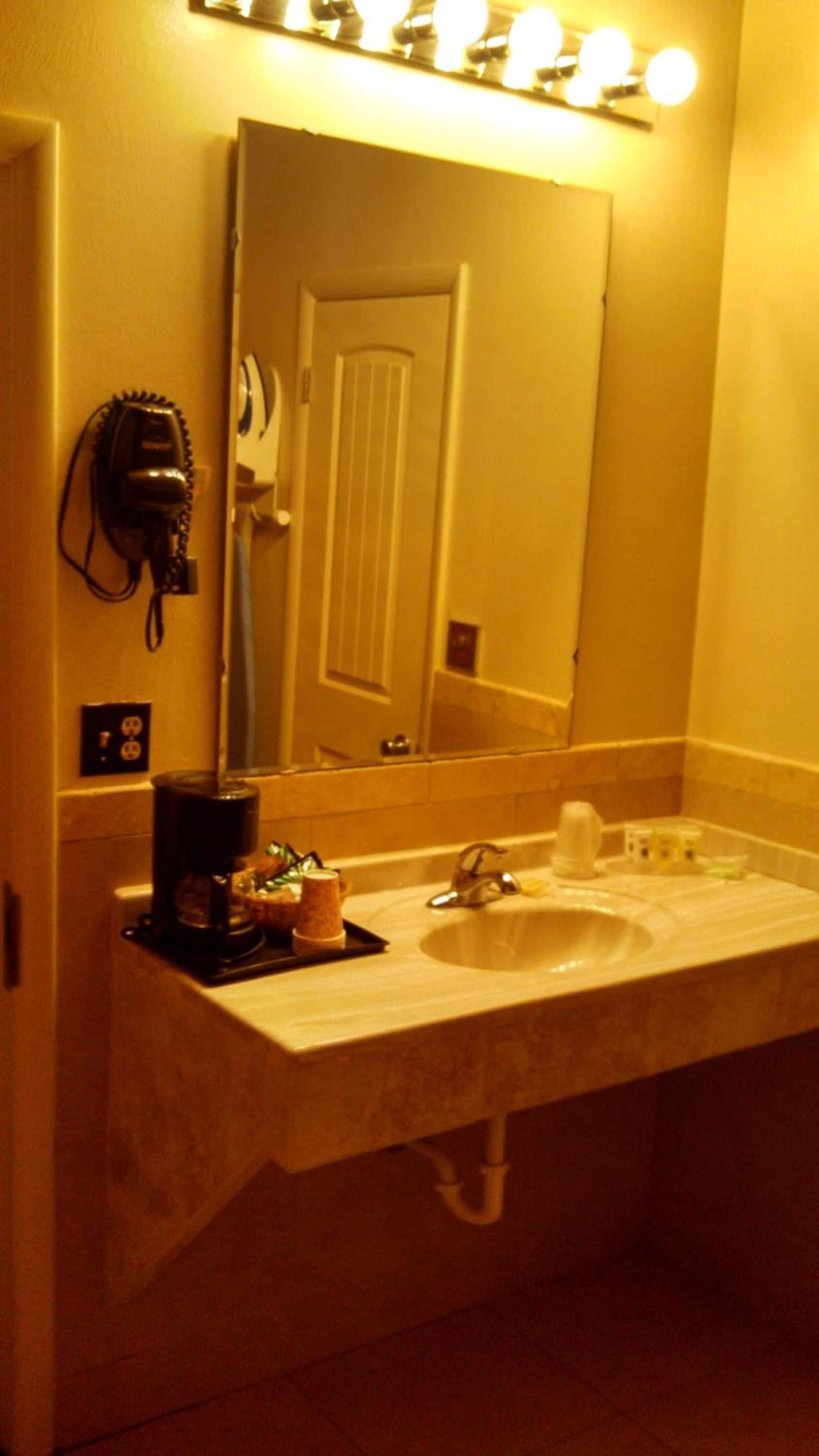 A bathroom with a sink, a hairdryer, and a mirror.