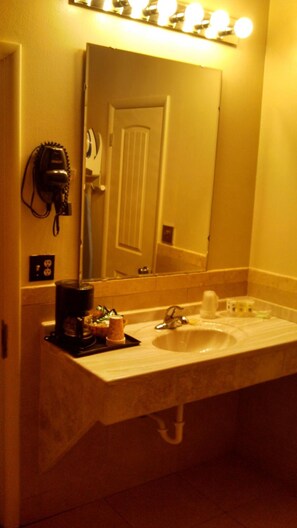 A bathroom with a sink, a hairdryer, and a mirror. - Trail's End Motel Sheridan (Sheridan)