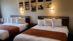 Une chambre d’hôtel avec deux lits, une chaise et des œuvres d’art accrochées au mur.