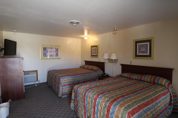 A hotel room with two beds, a desk, a chair, and a television. - Trail's End Motel Sheridan (Sheridan)