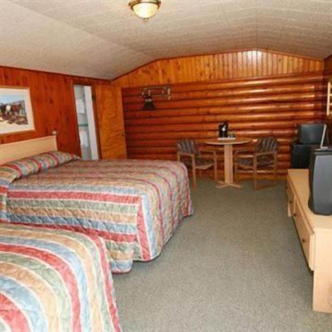 A room with two beds, a small table, and a chair.