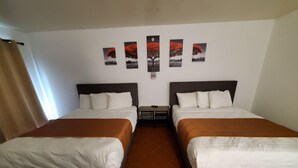 Une chambre d’hôtel avec deux lits, une table de chevet, une lampe fixée au mur et une fenêtre avec des rideaux.