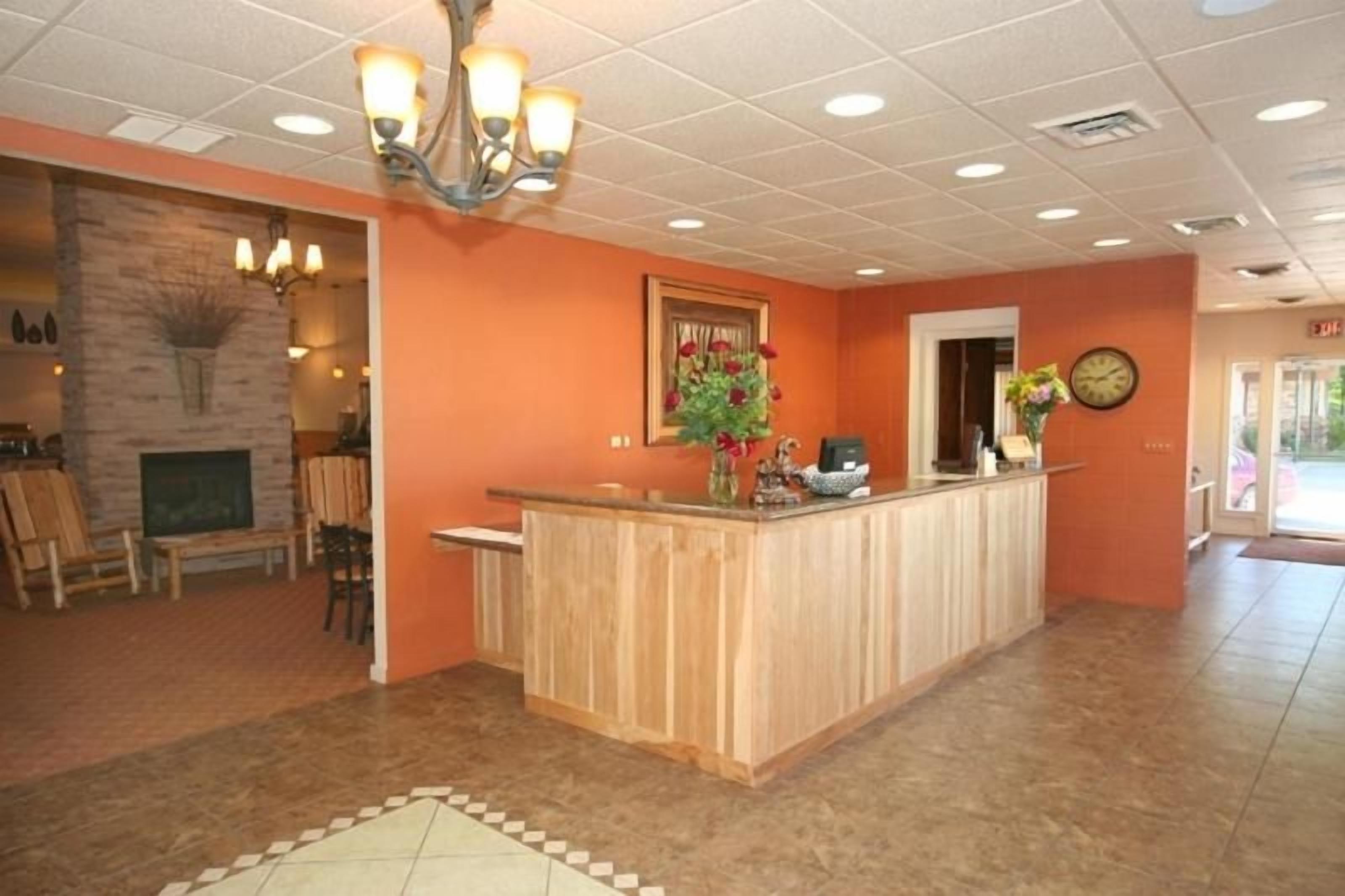 A reception area with a wooden counter, a clock, and a fireplace.