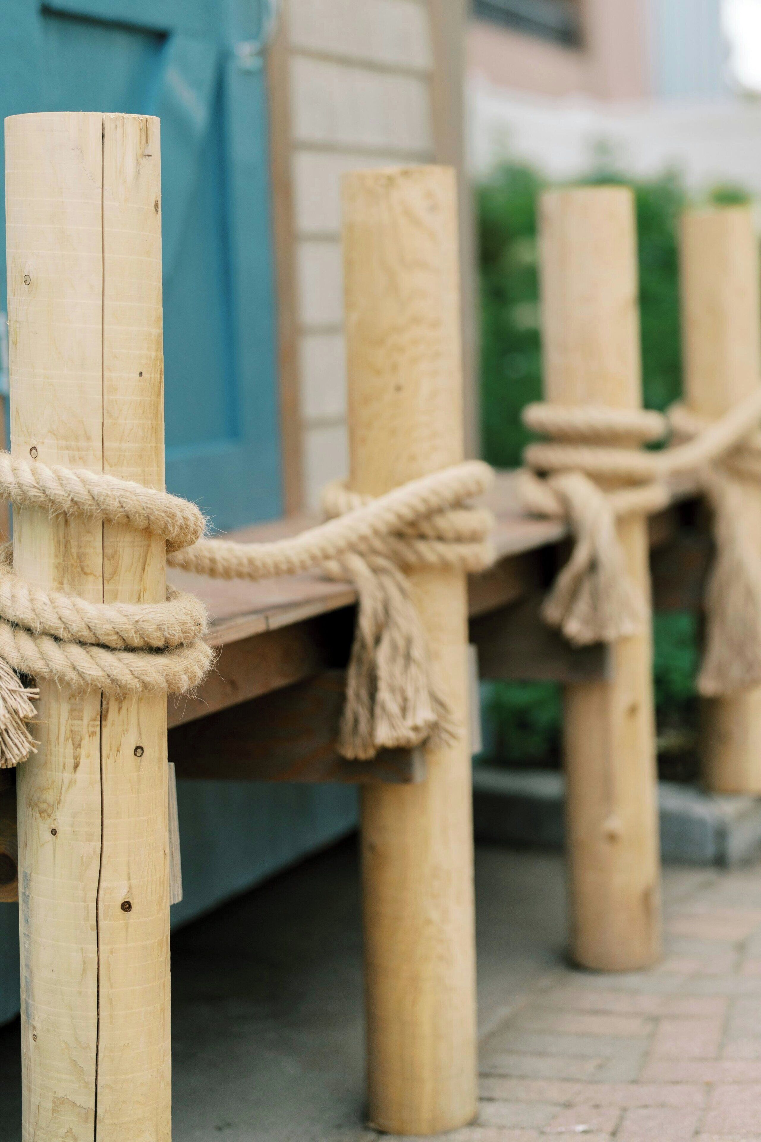 Un banc en bois, maintenu par des cordes et soutenu par des poteaux verticaux.