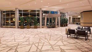 A spacious lobby with a patterned carpet, large windows, and several potted plants. - The Westin Edina Galleria (Edina)