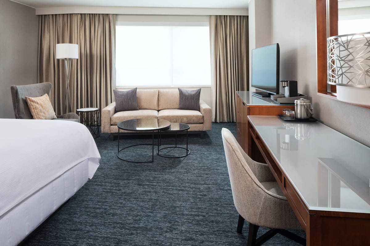 A hotel room with a bed, a sofa, a desk, a television, and a coffee table.