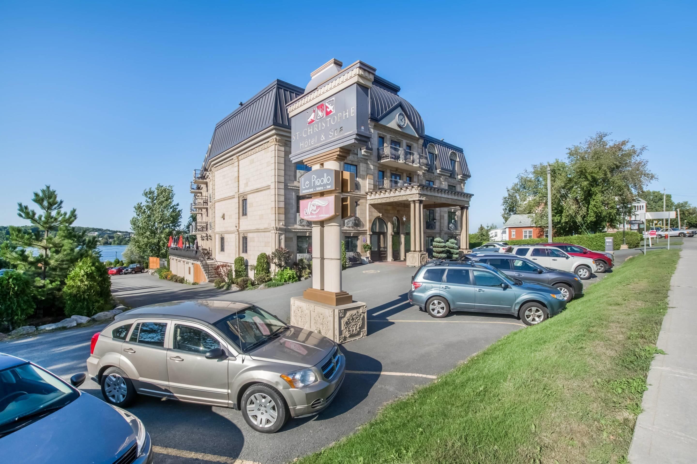 Een hotel met een klassieke architectuur, herkenbaar aan een opvallende ingang en een parkeerplaats met meerdere auto's.