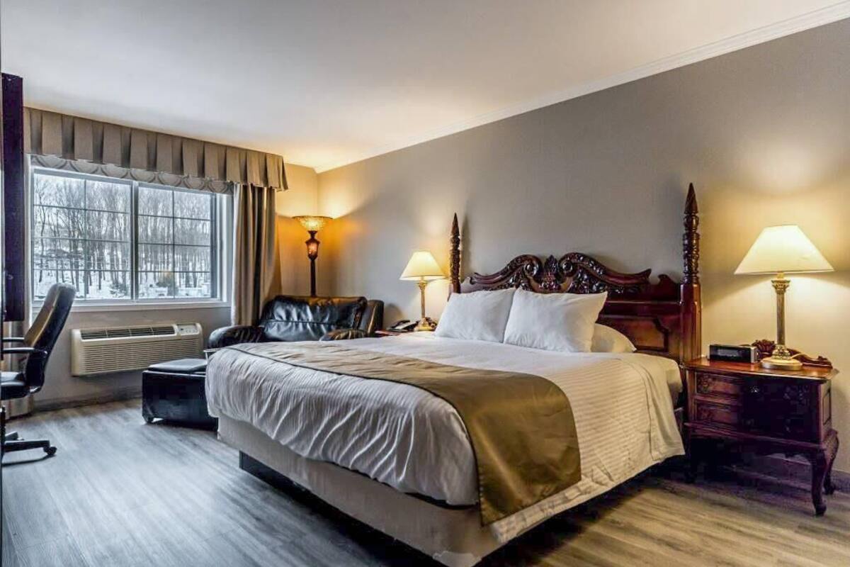 Una habitación de hotel con una cama grande, dos lámparas de noche, una silla y un escritorio.