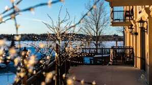 A balcony with a view of a snow-covered landscape and a building with a clock. - St Christophe Hotel & Spa, an Ascend Collection Hotel (Granby)