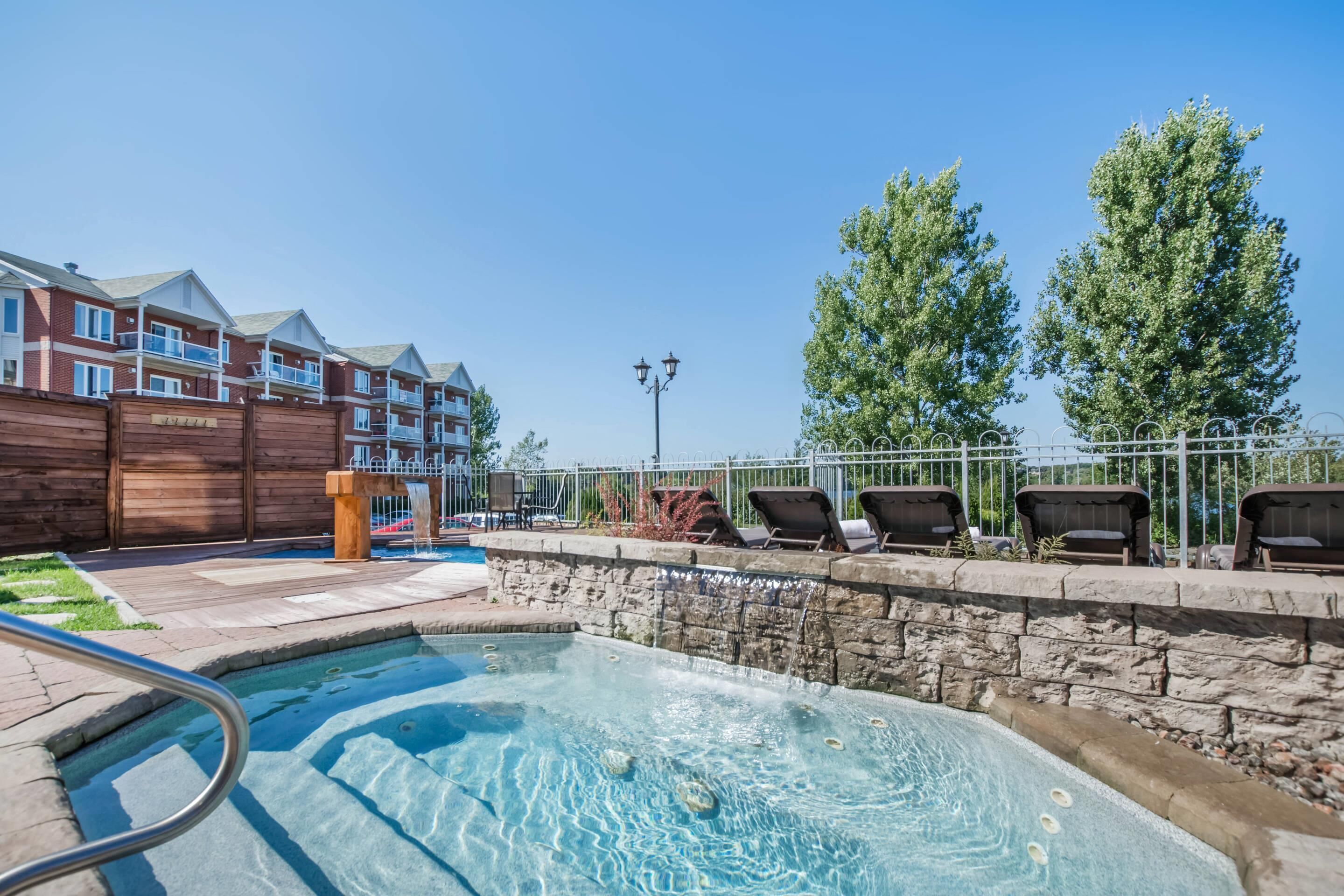Zona de piscina con jacuzzi, sillas de descanso y cerca de madera.