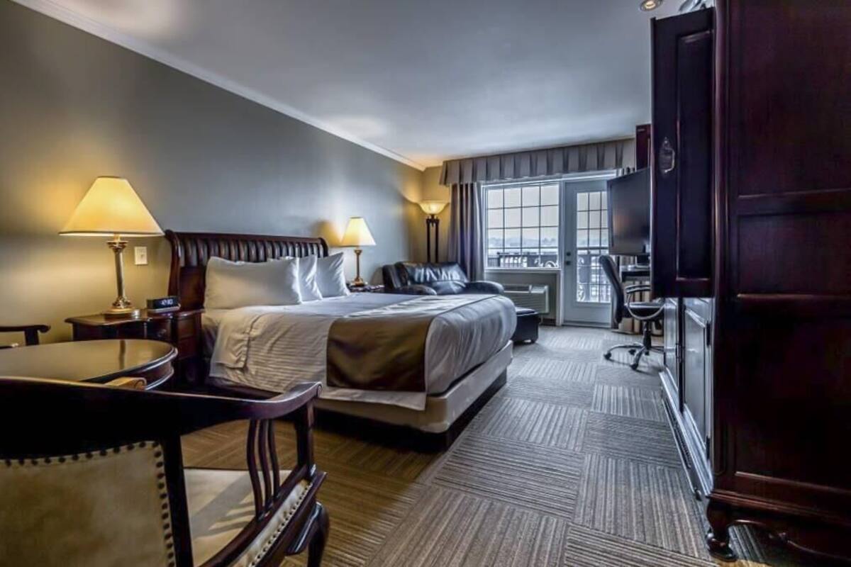 Habitación de hotel con una cama grande, dos lámparas de noche, un escritorio con una silla y vistas a la ciudad por la ventana.